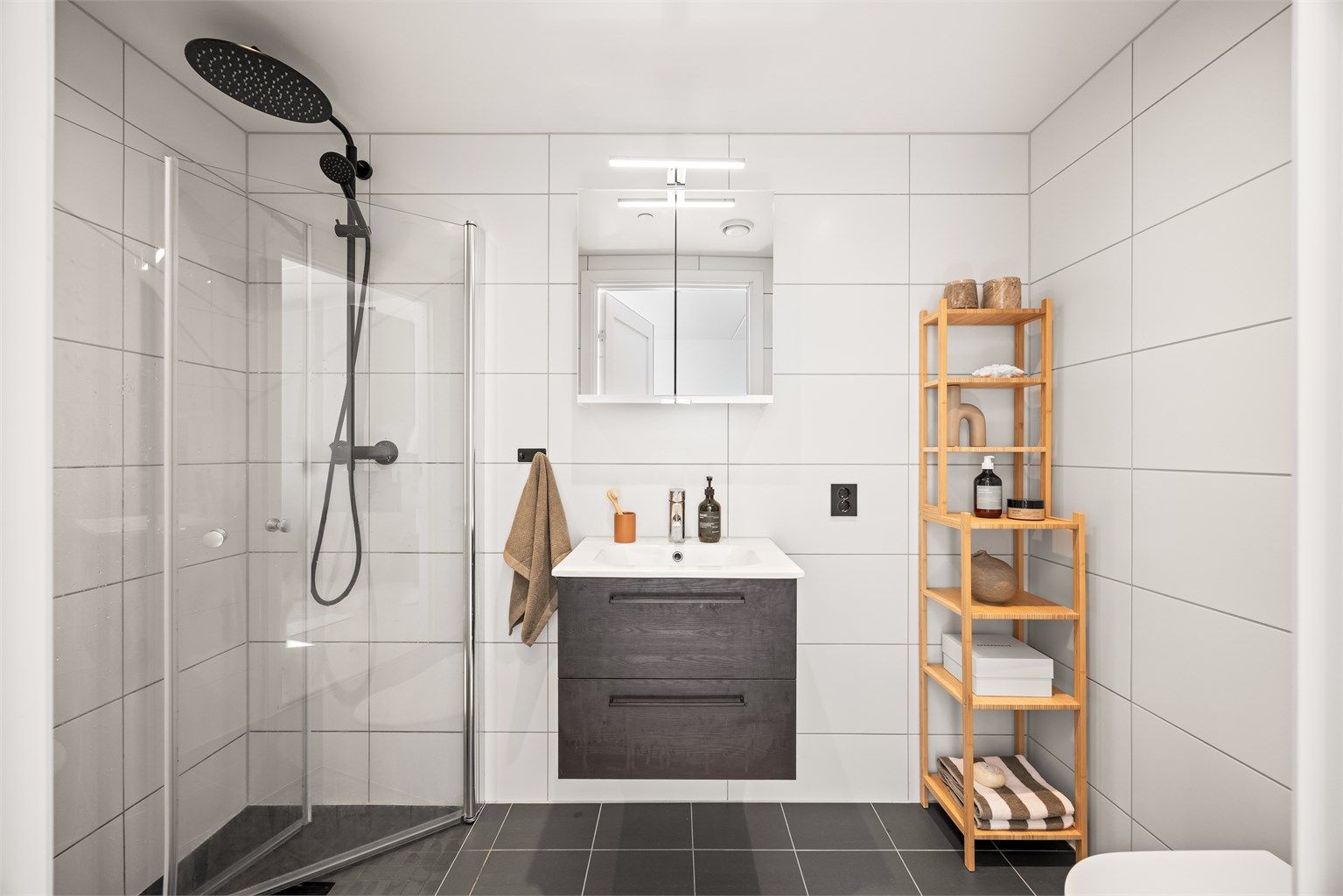 Badet er flislagt med gulvvarme, vegghengt servant og dusjnisje med innfellbare glassdører. 