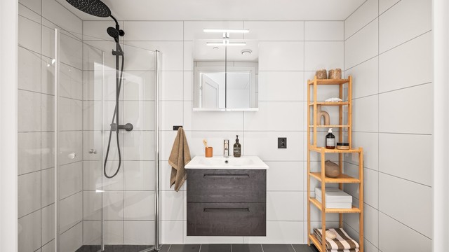 Badet er flislagt med gulvvarme, vegghengt servant og dusjnisje med innfellbare glassdører.