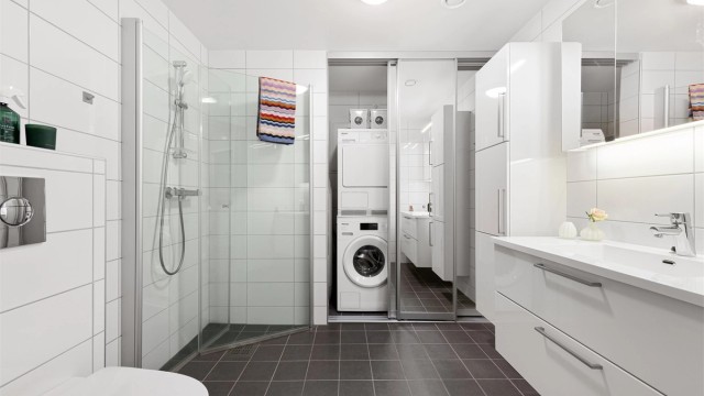 Flislagt bad med varmekabler i gulv. Det er skyvedørsfronter med speildører som skjuler varmtvannsbereder, stoppekran, opplegg for vaskemaskin og ventilasjonsaggregat.