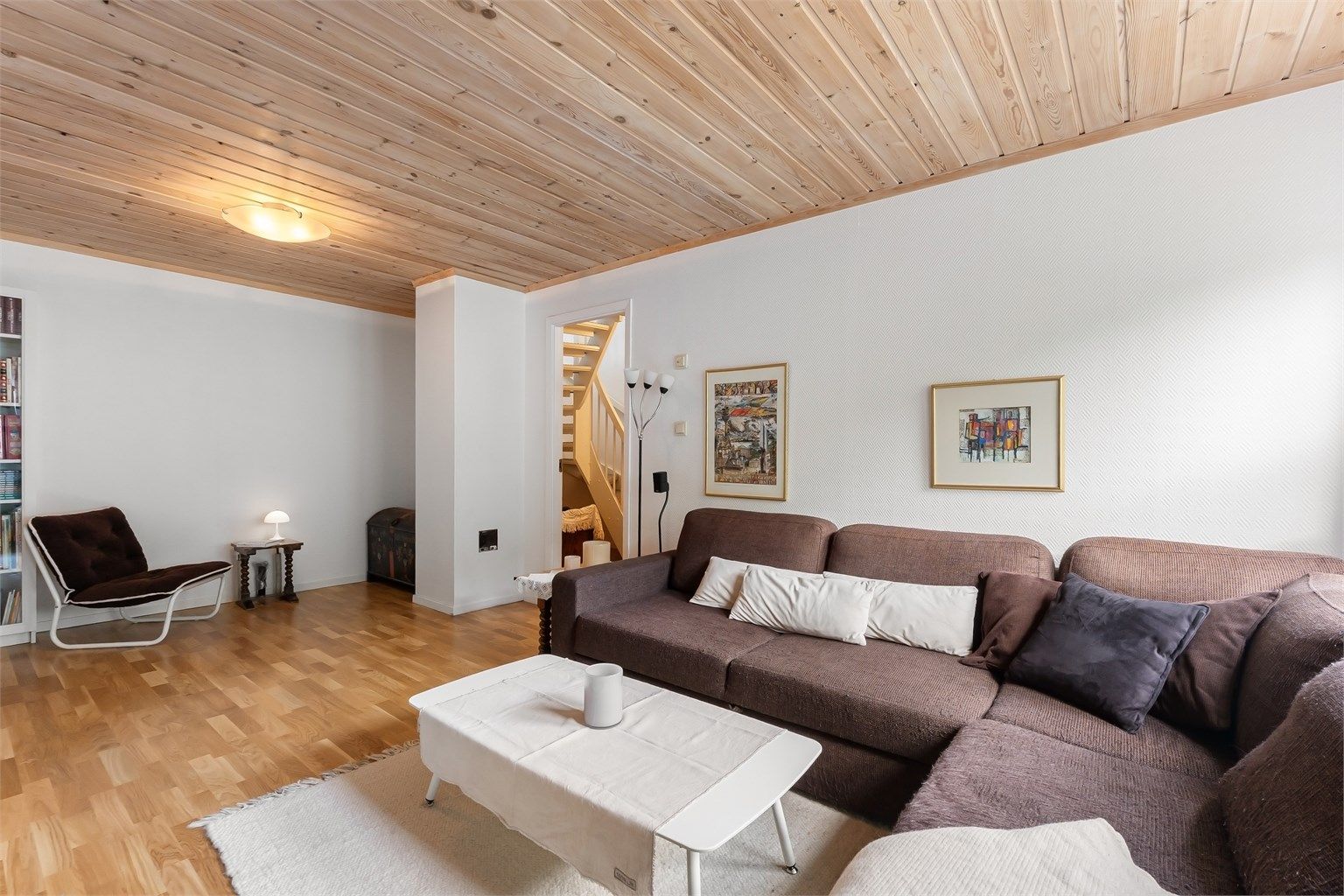 Rommet har panel i himlingen og parkett på gulvet, og trappeforbindelse opp til første etasje.
