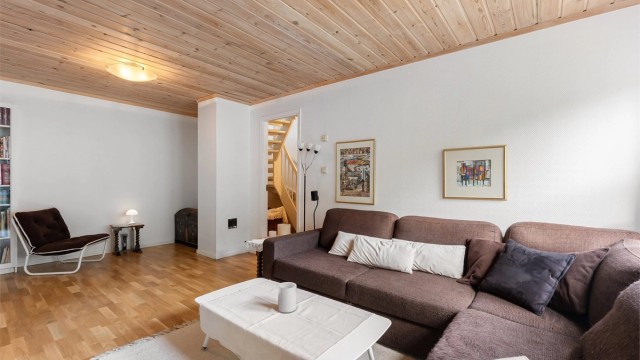Rommet har panel i himlingen og parkett på gulvet, og trappeforbindelse opp til første etasje.