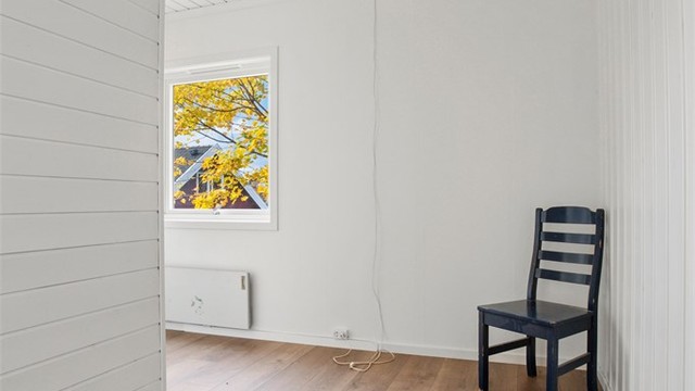 Lyst soverom med nytt gulv og utsikt mot hagen.