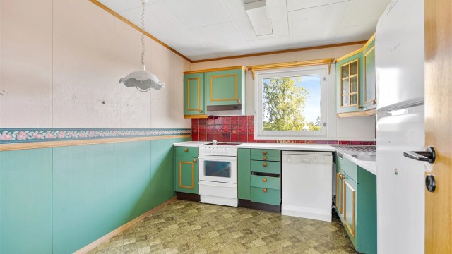 Kjøkkeninnredning fra byggeåret med laminert benkeplate og frittstående hvitevarer.