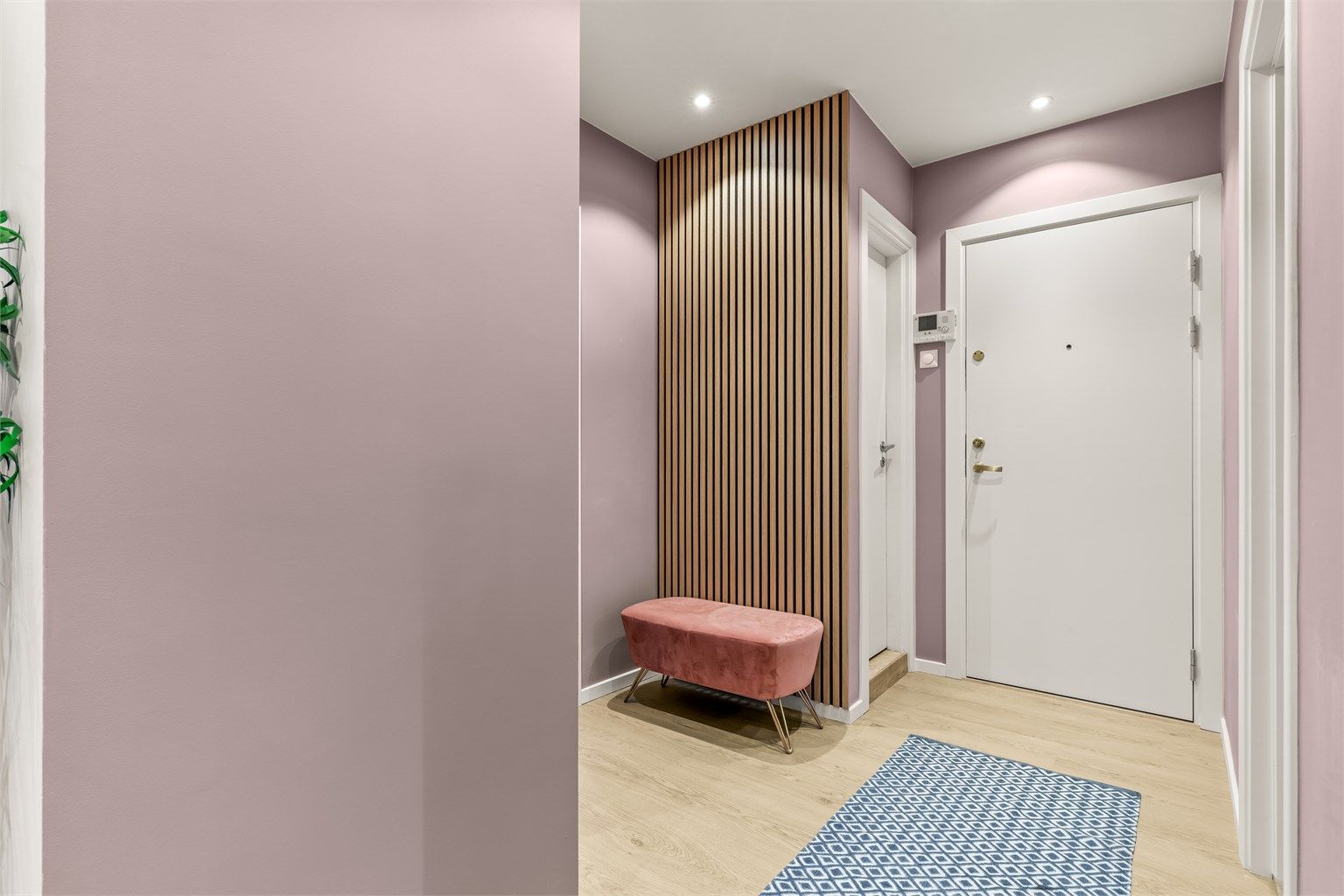 En spilevegg i tre gir en lun og moderne detalj i entreen.