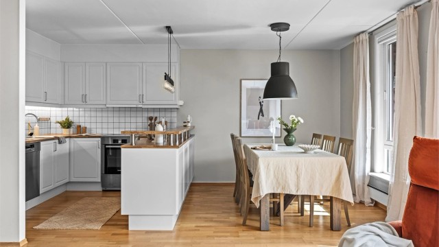 Åpen og lys kjøkkenløsning bestående av hvite profilerte fronter og laminert benkeplate.