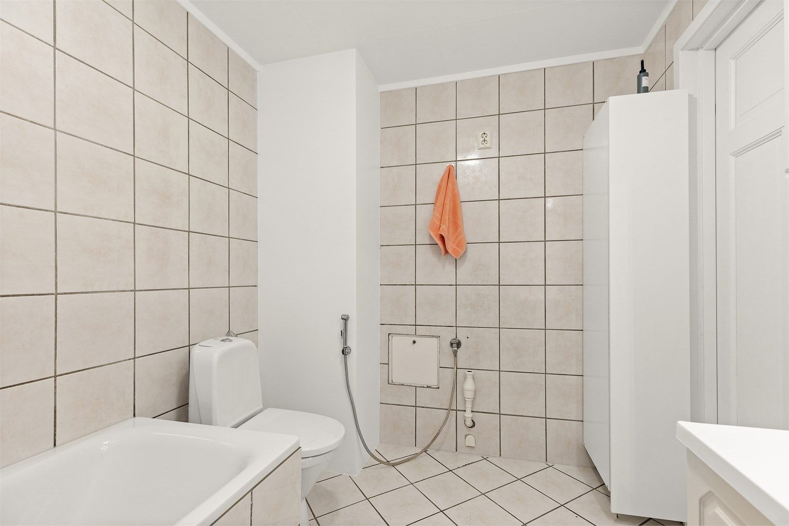 Gulvmontert toalett og flislagte gulv med elektrisk gulvvarme og flislagte vegger.