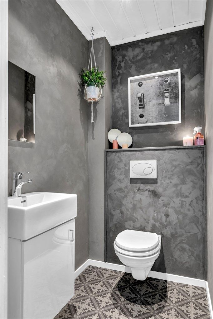 Toalettrommet har en vegghengt servant med underliggende skap, speil og vegghengt toalett.