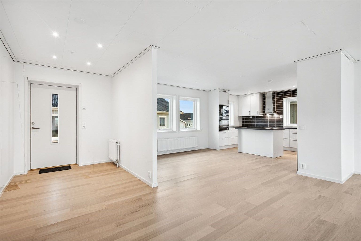 Lys og åpen entré gir et godt første inntrykk av boligen. Entréen er belyst med downlights og det er også radiator for oppvarming på siden.