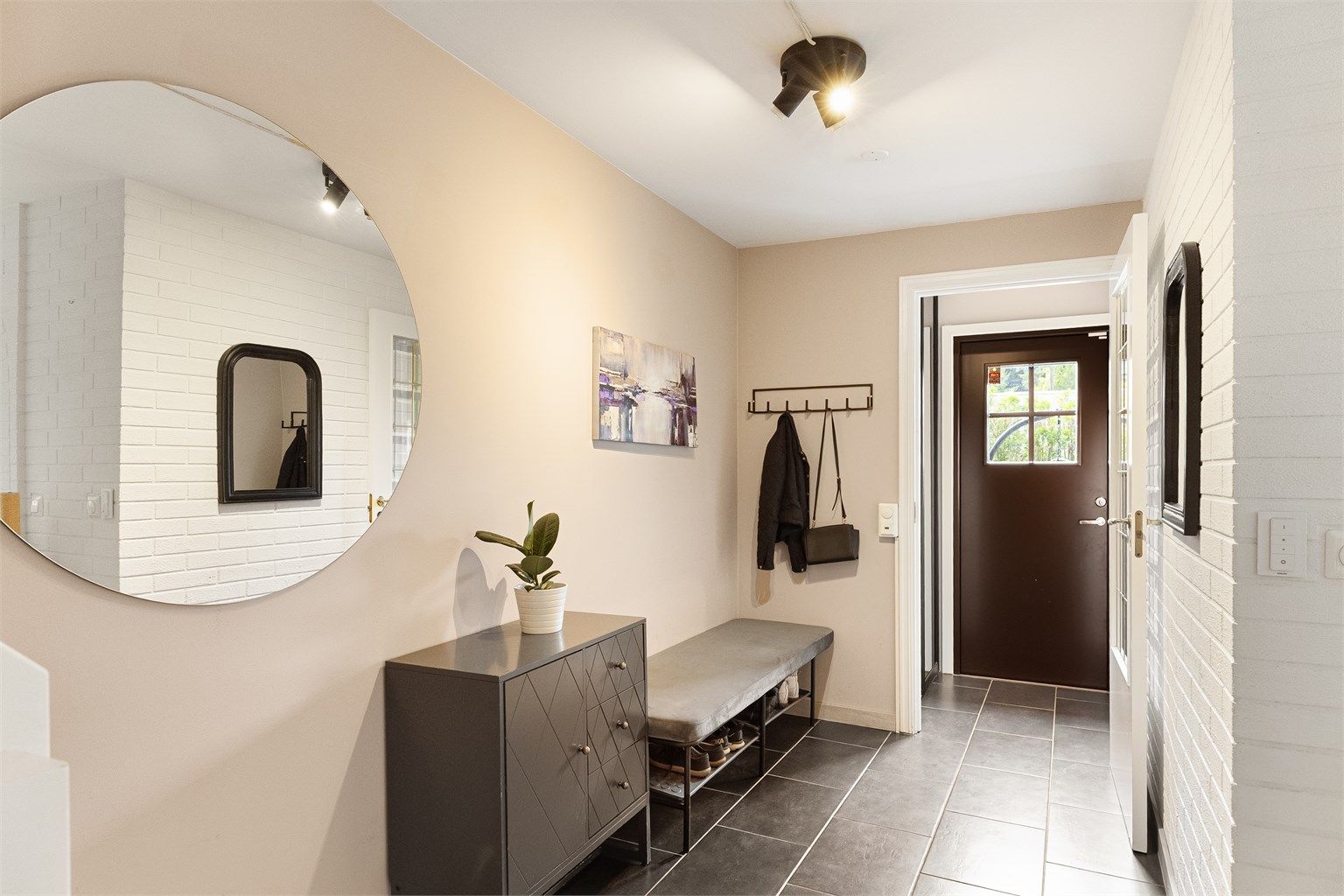 Entréen gir et ryddig og innbydende førsteinntrykk, med god plass og praktiske fliser på gulv. Entrédøren har glassfelt som slipper dagslys inn i gangen, og yttergangen kan lukkes av mot resten av boligen.