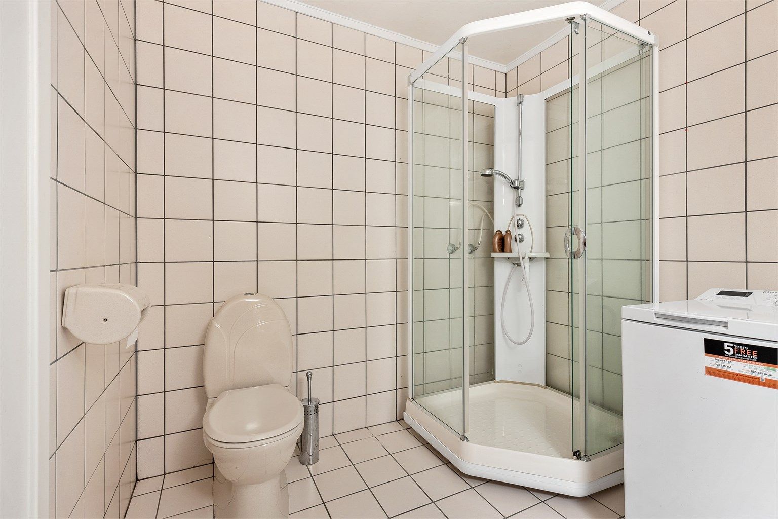 Badet har dusjkabinett med dusjarmatur og gulvstående toalett, samt opplegg for vaskemaskin. 
