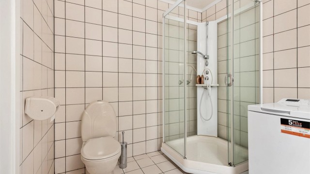 Badet har dusjkabinett med dusjarmatur og gulvstående toalett, samt opplegg for vaskemaskin.