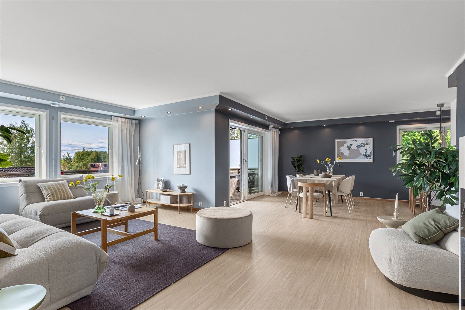 Boligens oppholdsrom fremstår åpent og luftig med mye naturlig lys