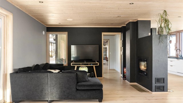 En sentralt plassert peisovn med glassdør gir ekstra varme og atmosfære i stuen.