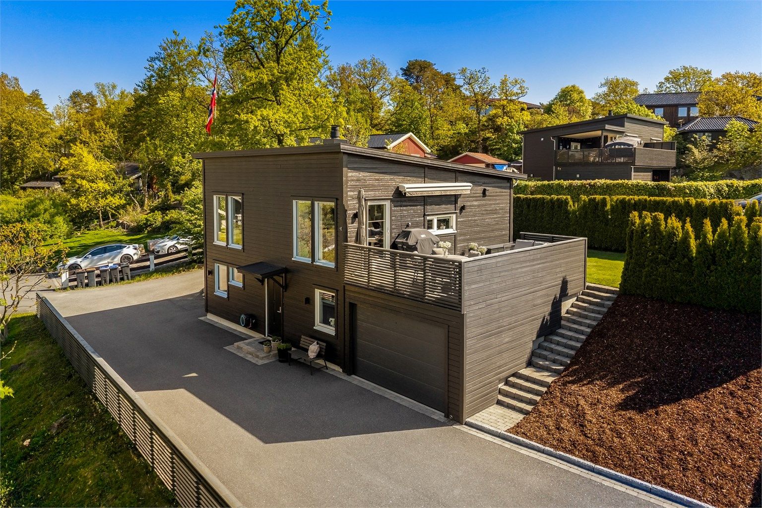 Velkommen til Brentåsveien 5B! Oversikt over boligen med garasje, terrasse og hage. Foto: [KRON Media / Karl Filip Kronstad]