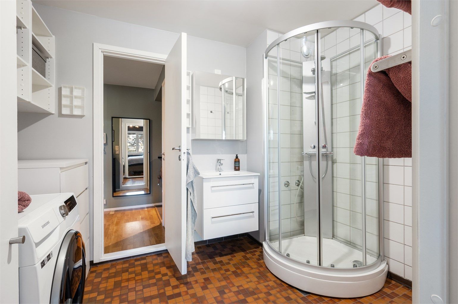 Baderommet har flislagt gulv med varmekabler, dusjkabinett og opplegg for vaskemaskin.