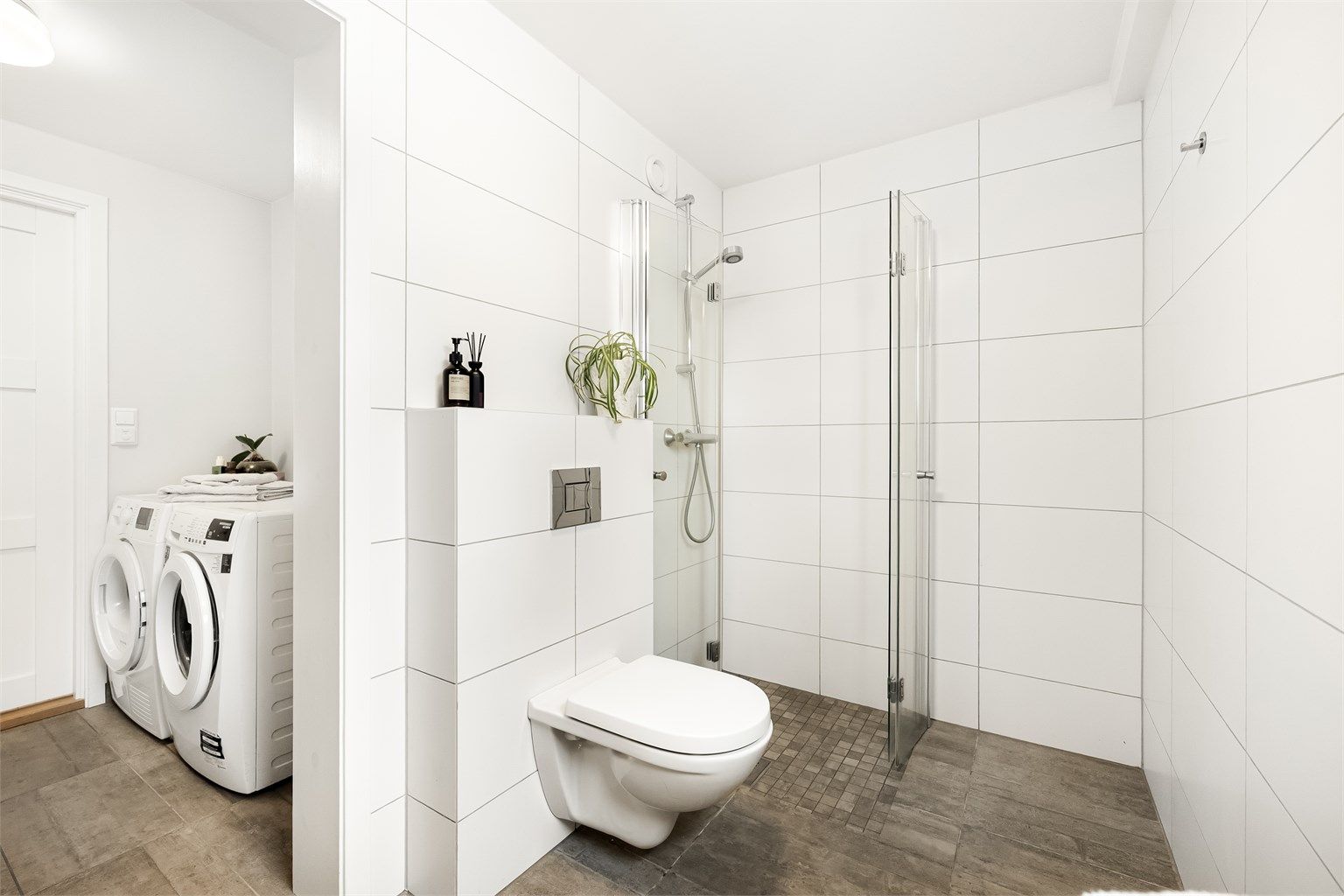  Dusjhjørne med innfellbare glassdører og vegghengt toalett.