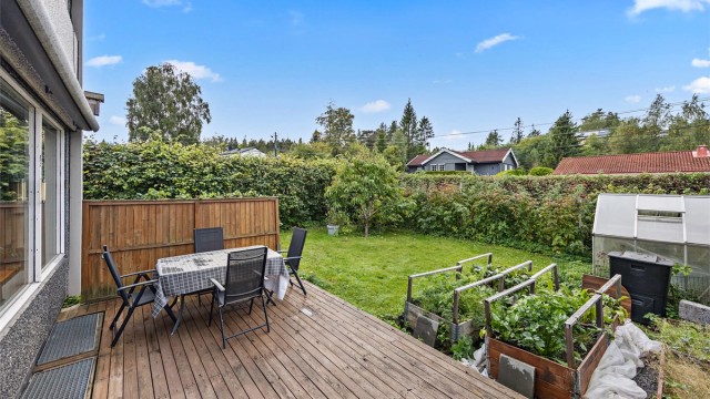 Hageområde med etablerte dyrkingskasser og skjermende hekk.