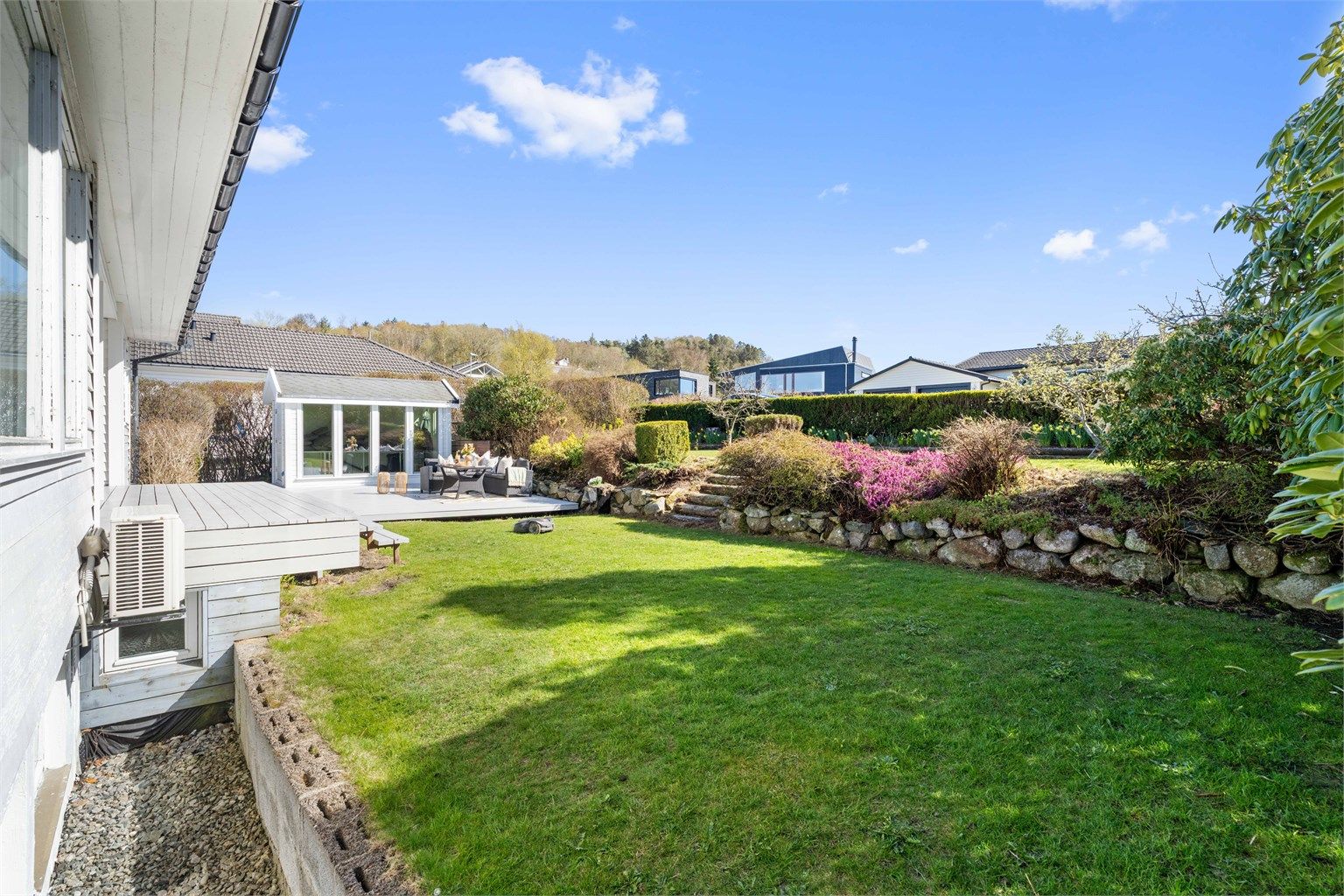 Stor, opparbeidet hage med plen og beplantning.