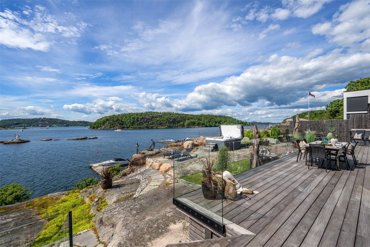 Utgang fra stue og spisestue i 1. etasje via store skyvedører til vestvendt terrasse oppført med vedlikeholdsvennlig tredekke og rekkverk i glass.