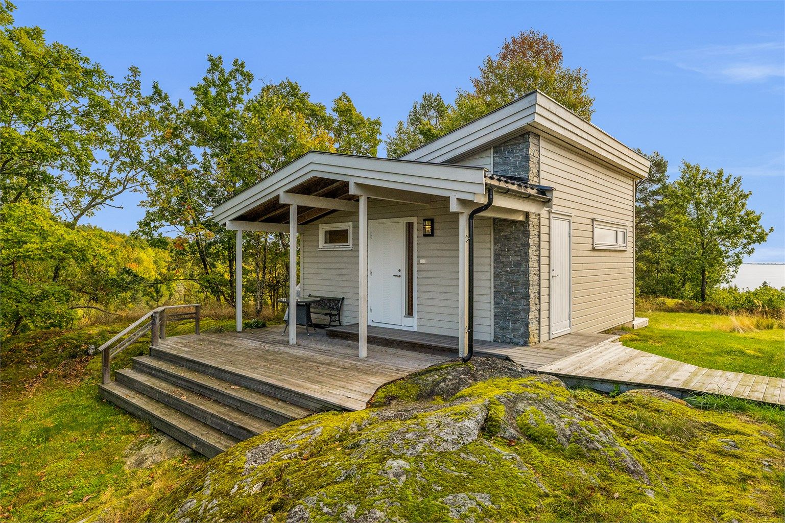 Annekset har en moderne arkitektur med overbygd inngangsparti og terrasse.