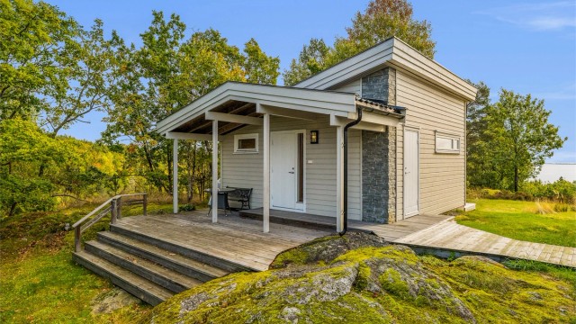 Annekset har en moderne arkitektur med overbygd inngangsparti og terrasse.