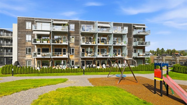 Blokken har koselig fasade med trekledning og luftige balkongener mot syd. Pent opparbeidede fellesarealer og fin lekeplass for de minste