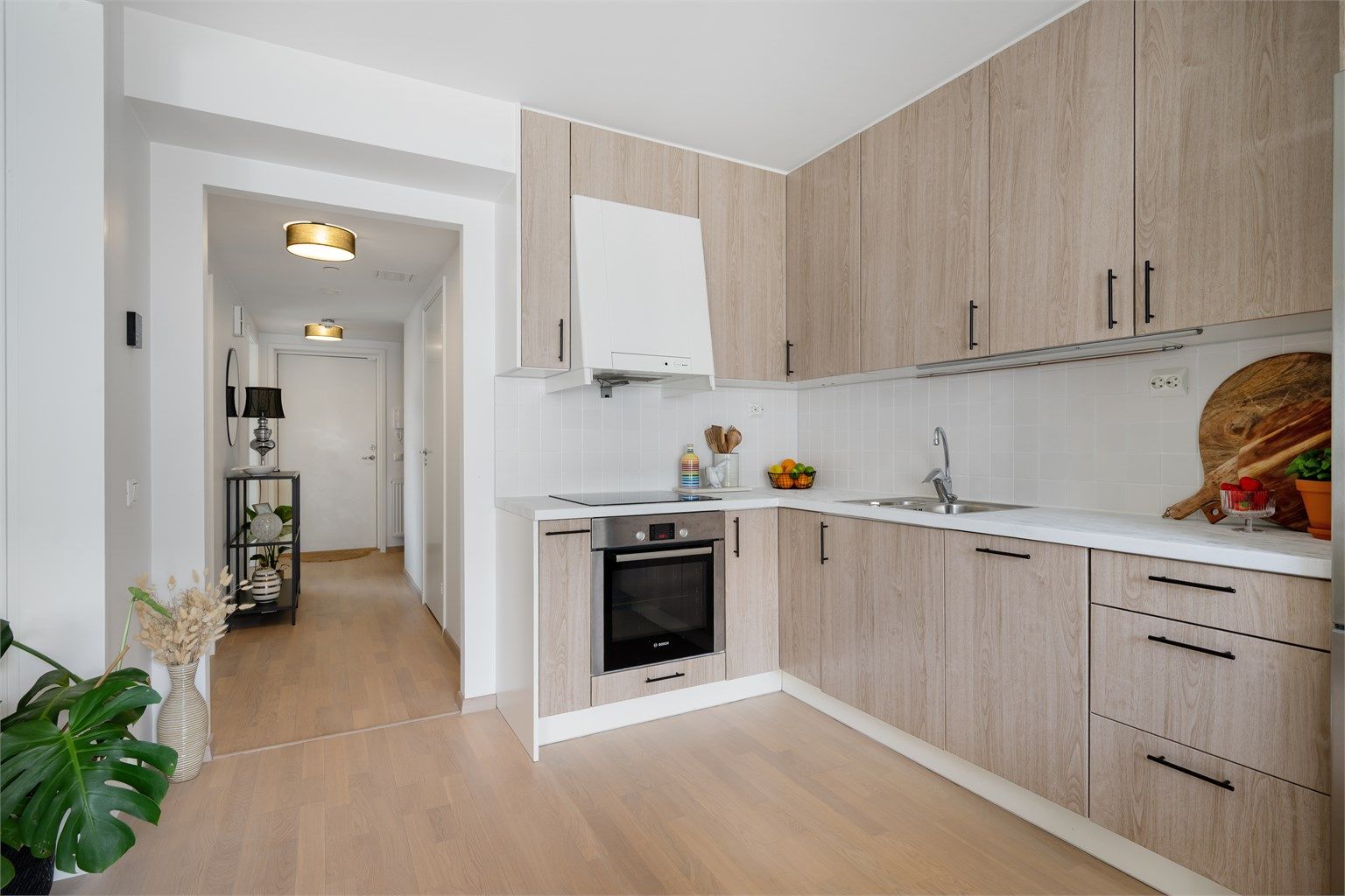 Lys og åpen kjøkkenløsning. Kjøkkeninnredning fra byggeår er oppgradert med folierte, glatte fronter og benkeplate i 2025.