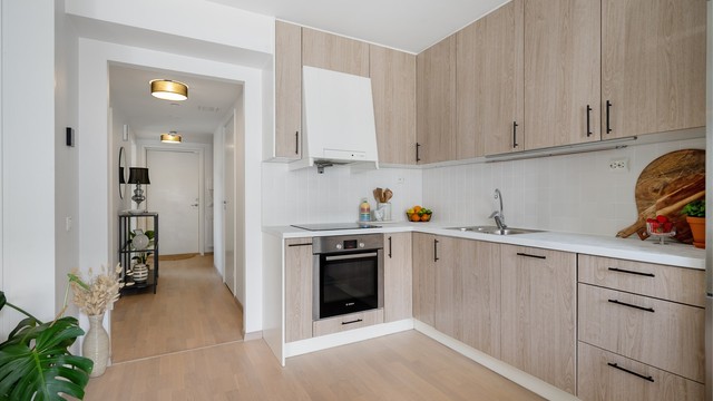 Lys og åpen kjøkkenløsning. Kjøkkeninnredning fra byggeår er oppgradert med folierte, glatte fronter og benkeplate i 2025.