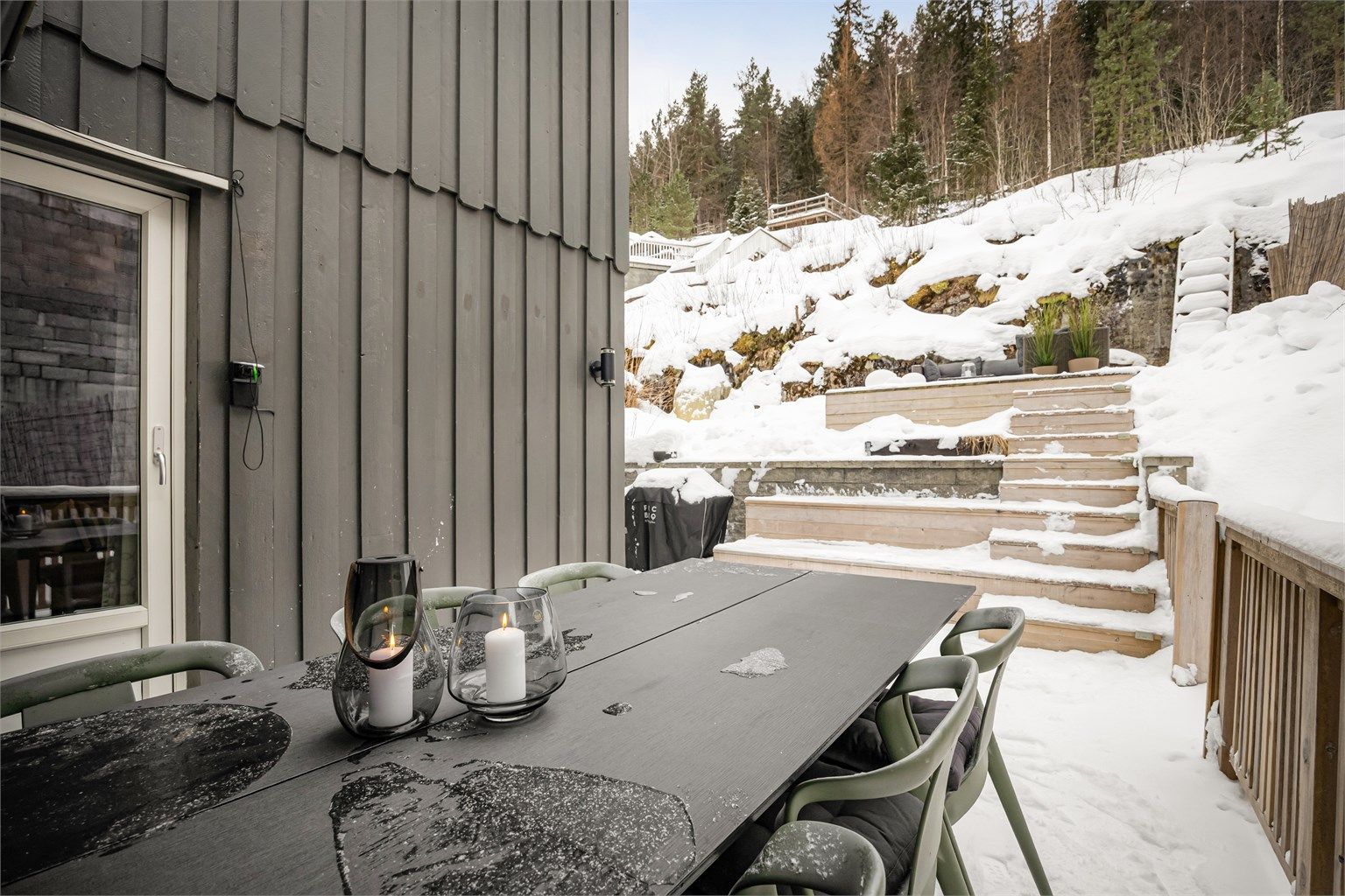 Utgang fra stue til platting med spiseplass og tilgang til terrasserte uteområder.