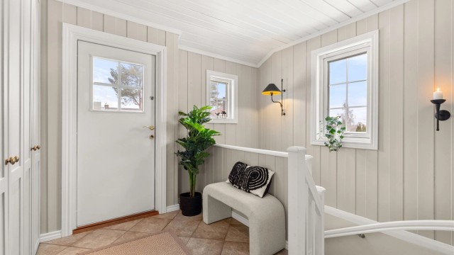 Romslig entré med gulvfliser med varmekabler og lys malt panel på vegger og i tak som gir et hyggelig førsteinntrykk. God plass til yttertøy i plassbygget garderobeskap. Utenfor ytterdøren er det også varmekabler i trapp/platting ved inngangspartiet