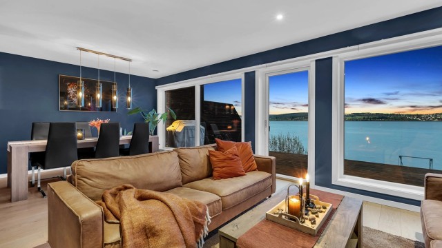 Moderne stue med downlights i himling, varmepumpe og store vinduer som slipper inn rikelig med naturlig lys