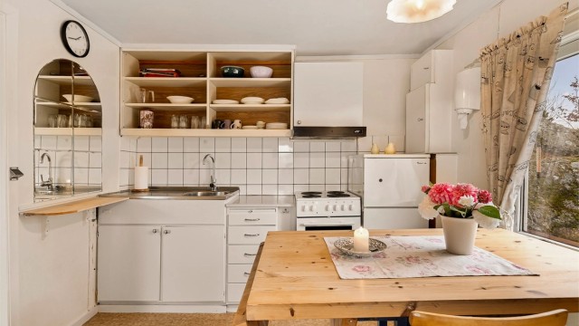 På kjøkkenet er det også plass til spisebord. Innredningen er enkel med malte fronter og åpne hyller istedenfor overskap.