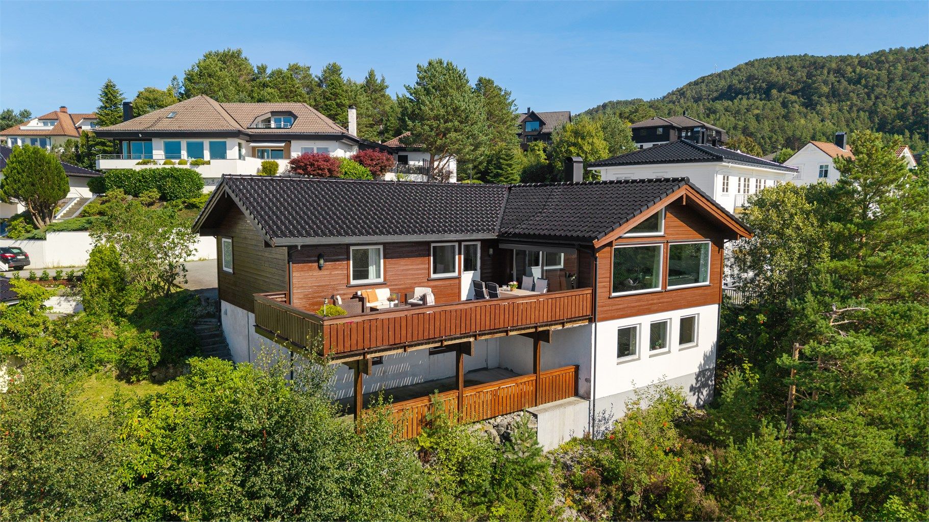 Fasade og solrik terrasse. Boligen har store vinduer og nydelig utsikt