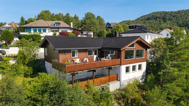 Fasade og solrik terrasse. Boligen har store vinduer og nydelig utsikt