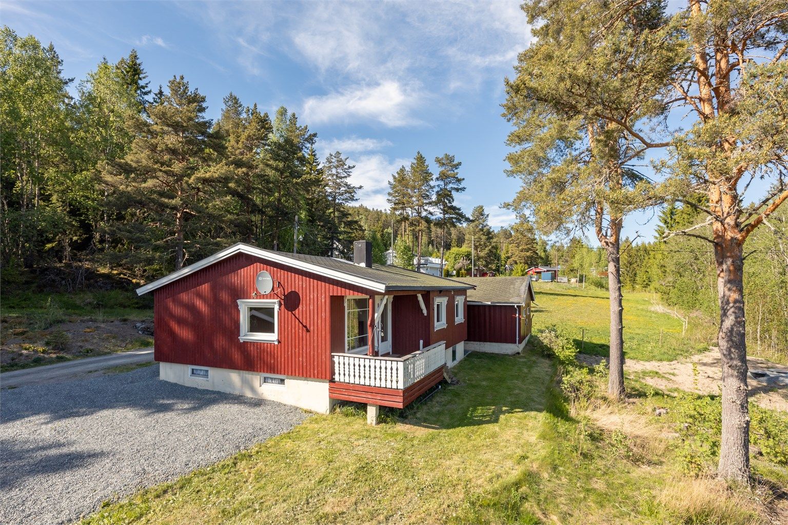Tomten er opparbeidet med gruset gårdsplass og plen, og grenser til naturtomt.