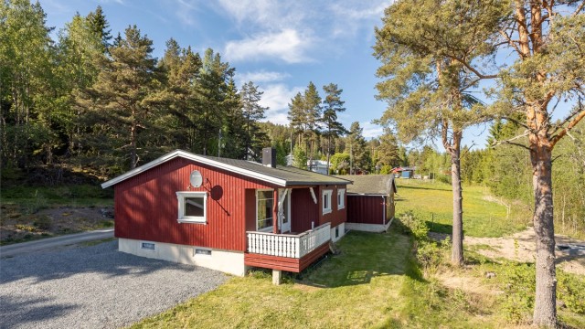 Tomten er opparbeidet med gruset gårdsplass og plen, og grenser til naturtomt.