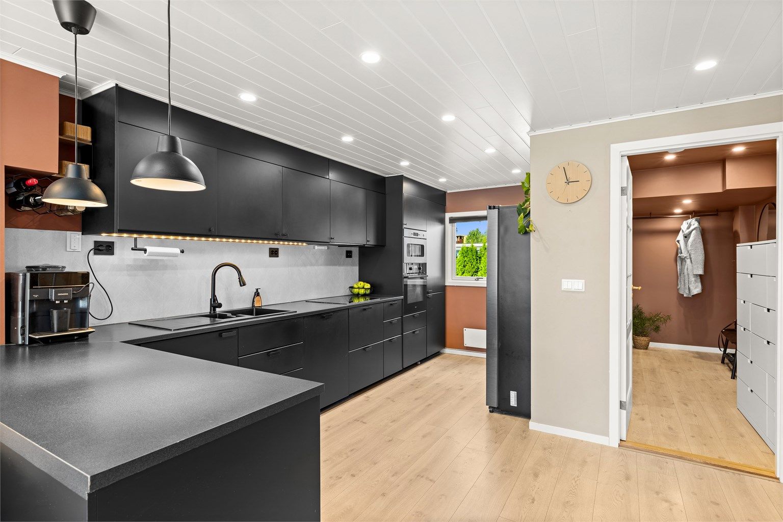 Kjøkkenet ligger i åpen løsning mot stuen med downlights i himling og lekker, stilren kjøkkeninnredning fra 2020. 