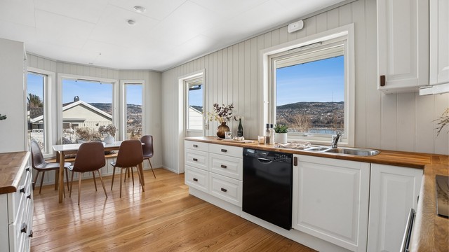 Kjøkkenet har profilerte fronter, benkeplate i tre og integrerte hvitevarer, og ligger i naturlig tilknytning til spisestuen.