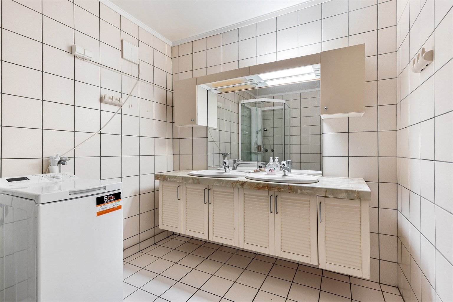 Baderom i kjelleretasjen er fra byggeår med flislagt gulv med varme og flislagte vegger. Badet har vegghengt servantinnredning, ovenpåliggende dobbeltservant med armaturer og vegghengt skap ved speil. 