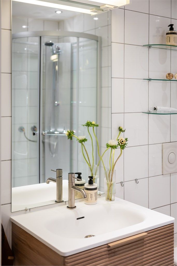 Speil og lysarmatur på vegg over servant.