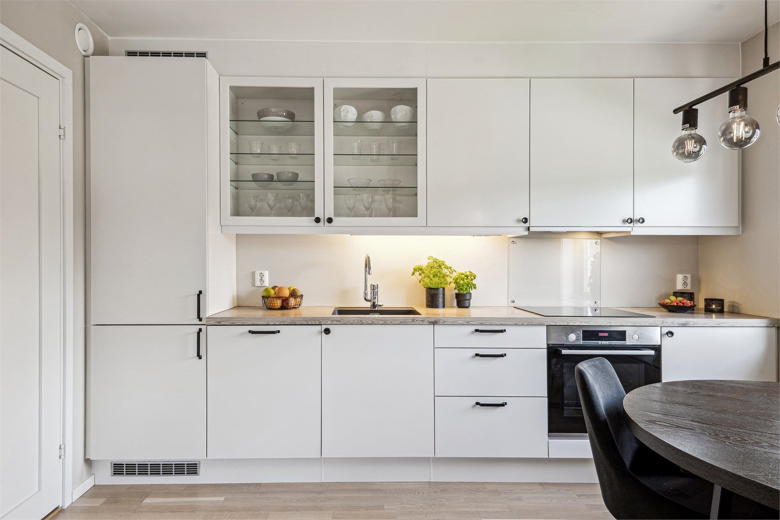 Kjøkkenet er innredet med hvite, glatte fronter. Underlimt oppvaskkum av kompositt, integrert komfyr, platetopp, integrert kjøl/frys og integrert oppvaskmaskin.