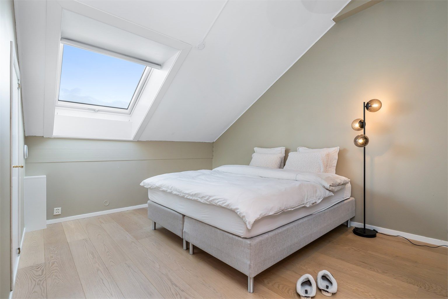 Lyst og romslig soverom i toppetasjen med skråtak og flotte gulvflater.