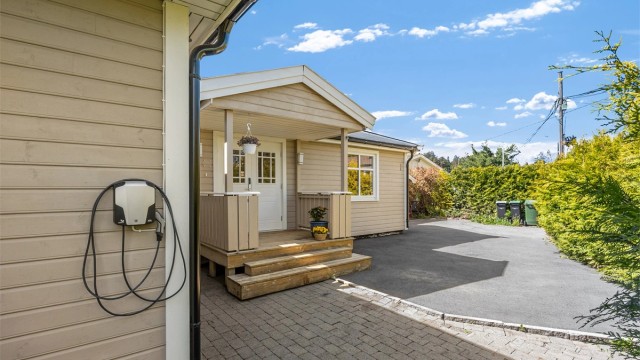 Ved inngangspartiet er det asfaltert gårdsplass og installert elbil-lader.