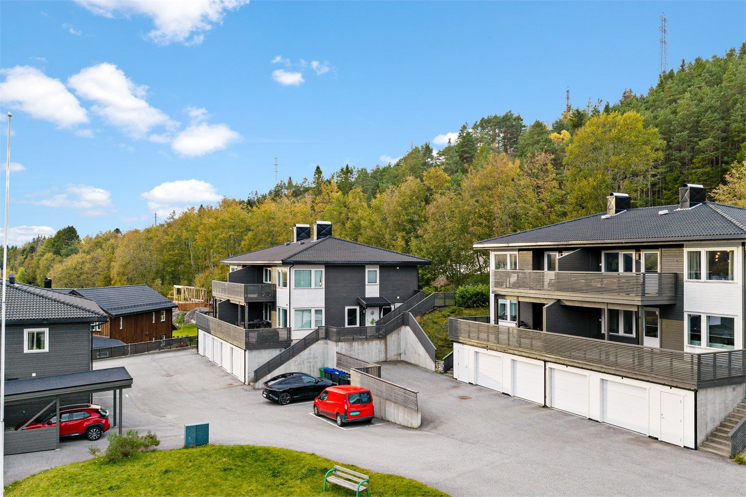 Asfaltert fellesareal med gjesteparkering og tilhørende garasjeplass i underetasjen.