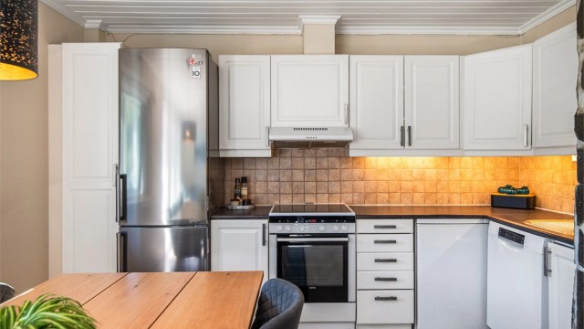 Kjøkkeninnredningen har profilerte fronter og laminert benkeplate, med flislagt felt mellom overskap og benkeplate.