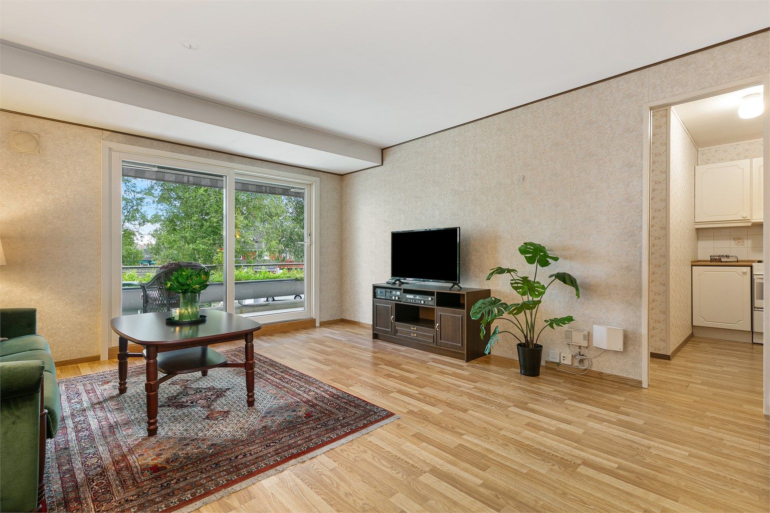 Lys og romslig stue med store vindusflater og utgang til en solrik terrasse, samt plass til både sofakrok og spisebord.