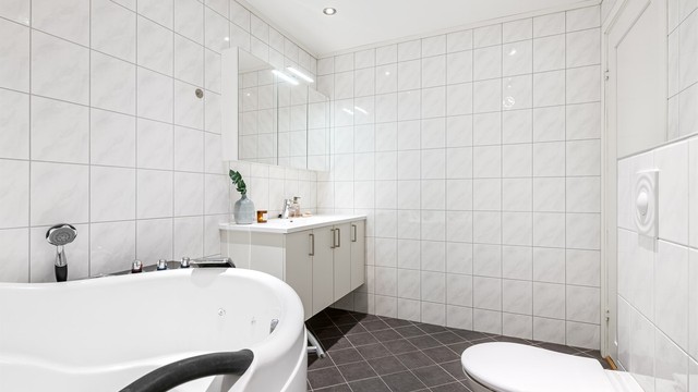 Vegghengt servantinnredning med speilskap og vegghengt toalett.