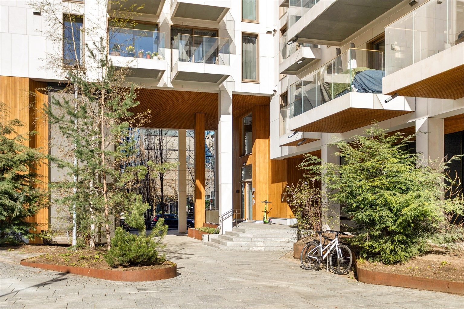 Pent opparbeidede fellesarealer med sykkelparkering og en innbydende inngang.