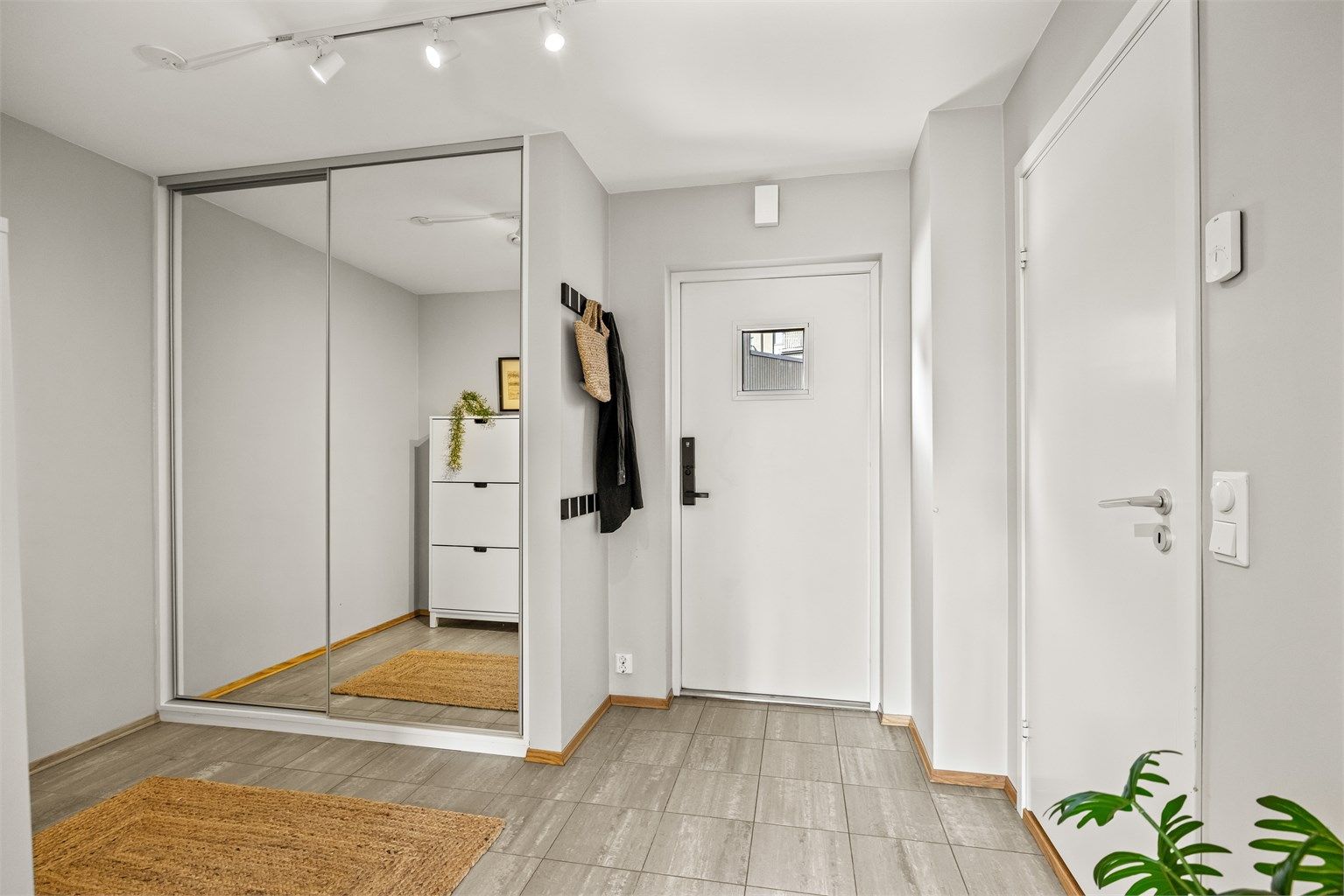 Entréen har flislagt gulv og en romslig skyvedørsgarderobe med speilfronter.
