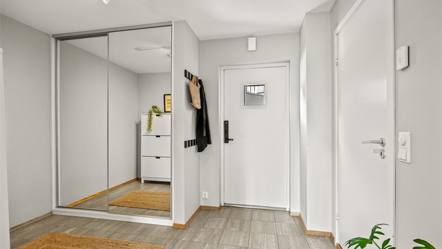 Entréen har flislagt gulv og en romslig skyvedørsgarderobe med speilfronter.
